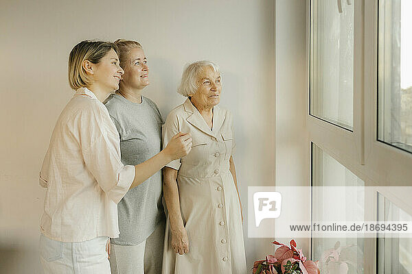 Frauen aus mehreren Generationen schauen zu Hause aus dem Fenster