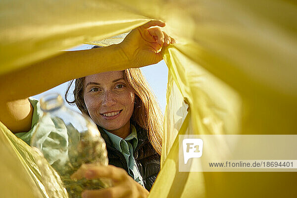 Smiling woman looking inside yellow garbage bag