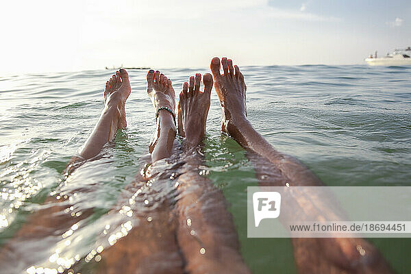 Legs of couple floating in sea