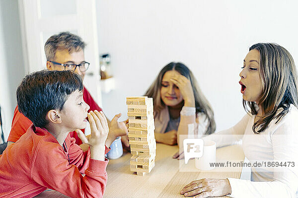 Mother and father playing block removal game with children at home