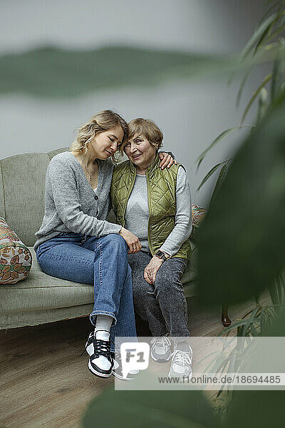 Großmutter und Enkelin sitzen zusammen im Wohnzimmer
