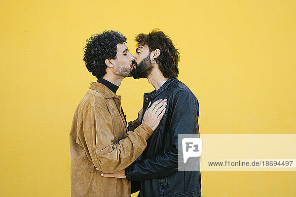 Romantisches schwules Paar  das sich vor gelbem Hintergrund küsst