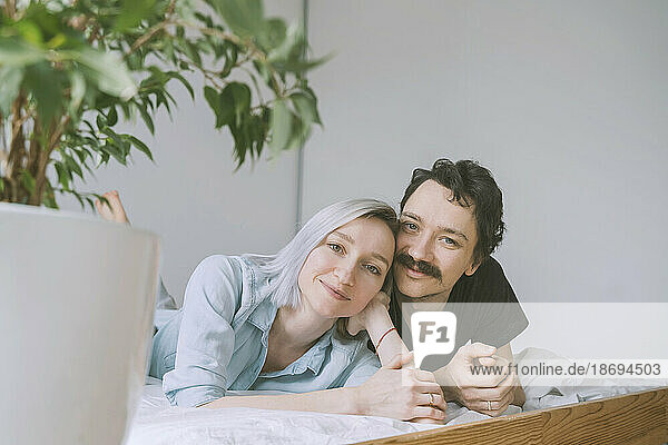 Smiling woman and man resting on bed at home