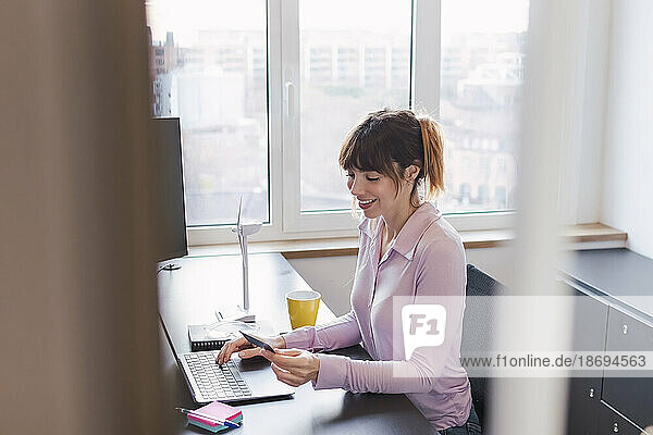 Smiling businesswoman using credit card in office