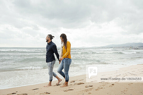 Reifer Mann und Frau gehen gemeinsam an der Küste am Strand spazieren