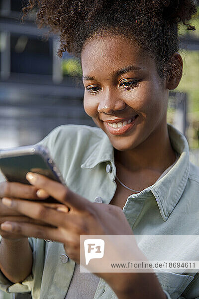 Smiling young woman surfing net through smart phone