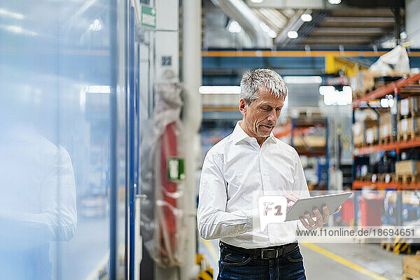 Mature businessman using tablet PC in factory