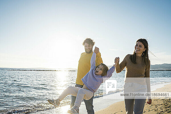 Happy parents playing with daughter at beach