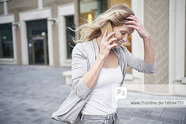 Blond woman with hand in hair talking on mobile phone
