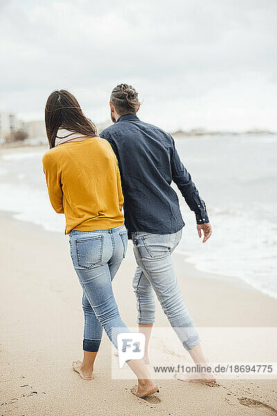 Mann und Frau gehen gemeinsam am Strand spazieren