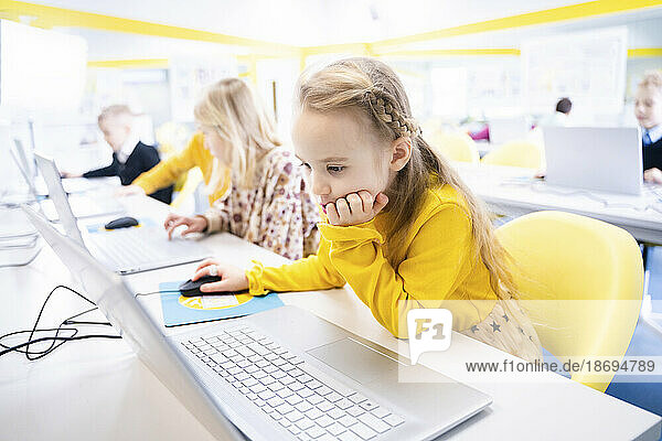 Blondes Schulmädchen lernt im Computerunterricht am Laptop