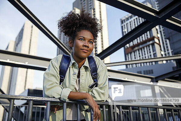 Woman with curly hair leaning on railing