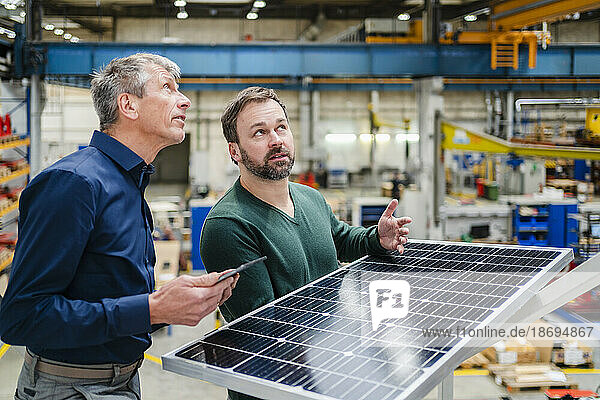 Manager and businessman discussing over solar panel at factory