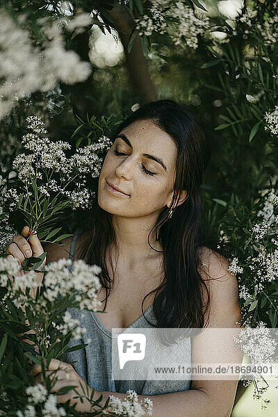 Woman with eyes closed amidst flowers