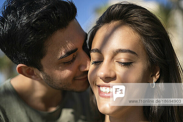 Young man embracing woman on sunny day
