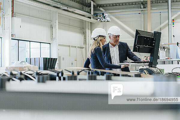 Geschäftsmann und Kollege arbeiten am Desktop-PC in der Fabrik