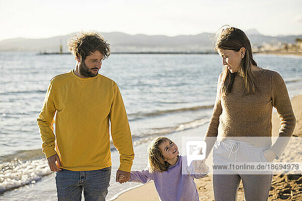 Vater und Mutter gehen mit Tochter am Strand spazieren