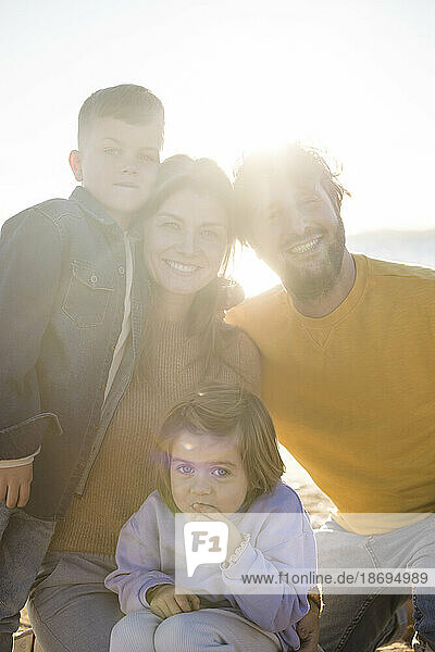 Lächelnde Eltern mit Sohn und Tochter am Strand an einem sonnigen Tag