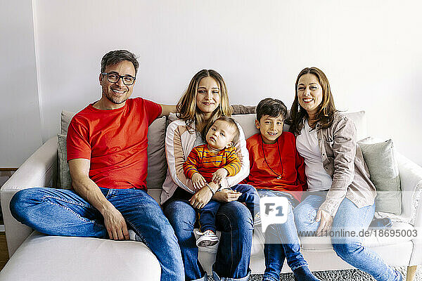 Smiling family sitting with children on sofa at home