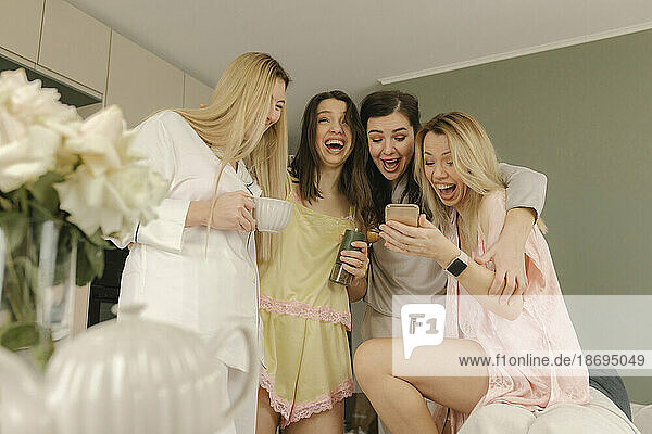 Glückliche Freunde  die Spaß mit einer Frau haben  die zu Hause ihr Smartphone hält