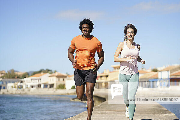Couple doing running exercise on pier near sea in coastal area