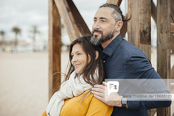 Smiling man and woman leaning on wooden lifeguard hut