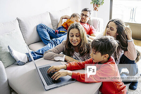 Boy using laptop by family sitting in living room at home