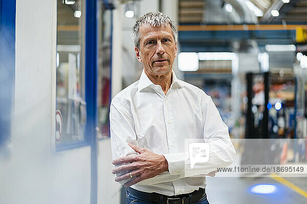 Mature businessman standing with arms crossed in industry