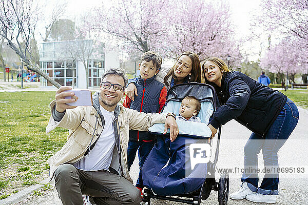 Man taking selfie with family through mobile phone at park