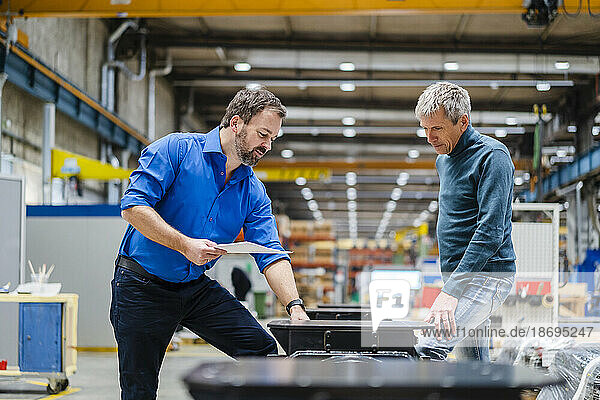 Manager explaining machinery to businessman at factory