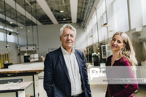 Happy businesswoman with senior businessman in factory