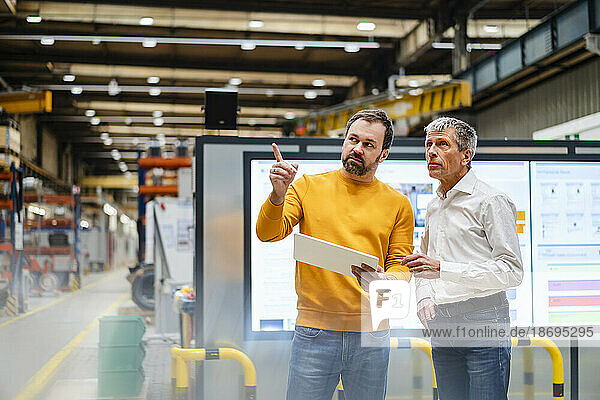 Businessman explaining and having discussion with colleague in factory