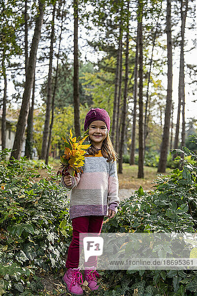 Smiling girl holding bunch of leaves
