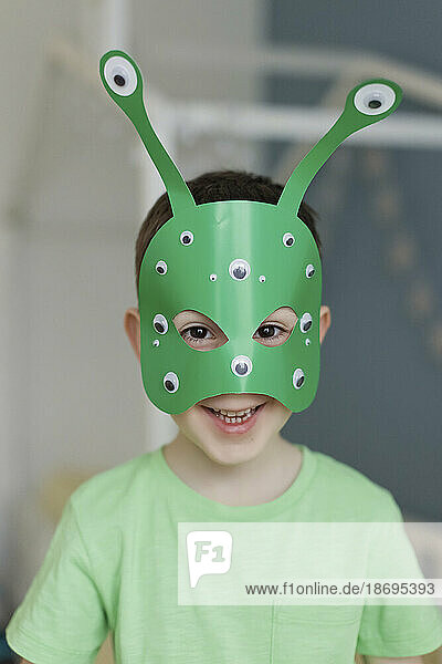 Smiling boy wearing green alien mask