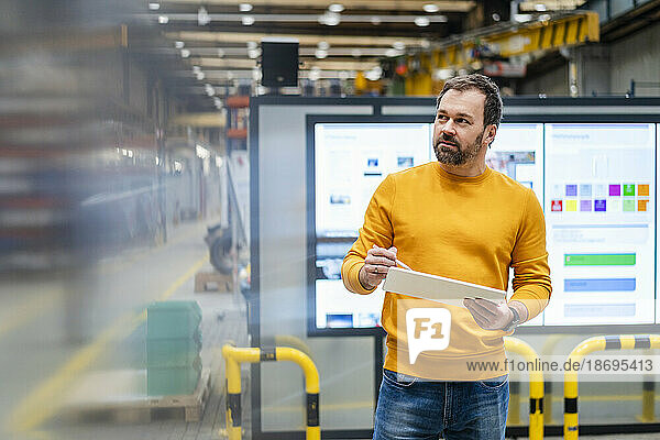 Reifer Mann hält Tablet-PC in der Fabrik