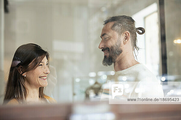 Lächelndes Paar im Café  gesehen durch Glasfenster