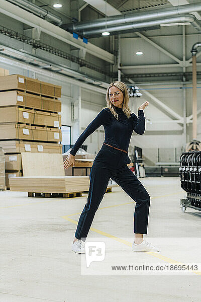 Smiling businesswoman dancing in carpentry factory