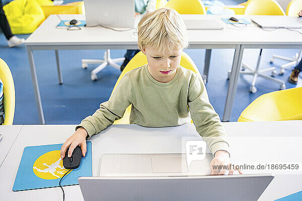 Boy using laptop sitting at desk in computer class