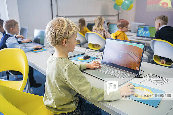 Junge lernt am Laptop und sitzt im Computerunterricht in der Schule