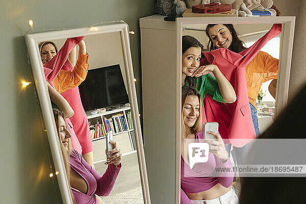 Frau macht zu Hause ein Spiegel-Selfie mit Freunden über ihr Mobiltelefon