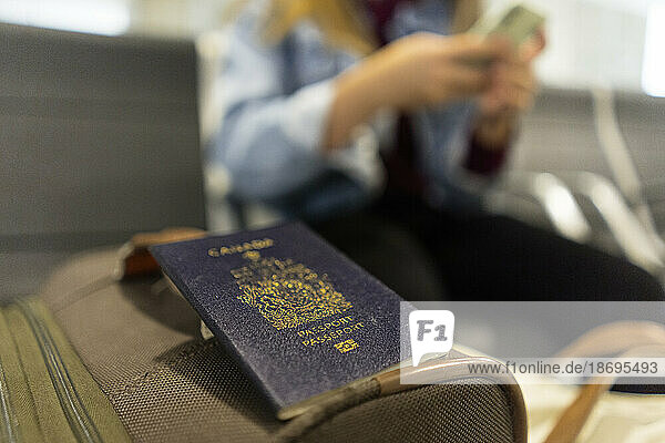 Passport on luggage with woman in background at airport