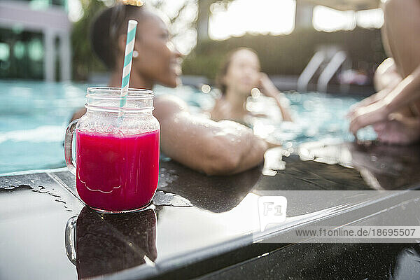Frischer Saft im Einmachglas mit Freunden beim Schwimmen im Resort
