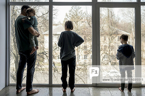 Vater und Söhne schauen zu Hause aus dem Fenster