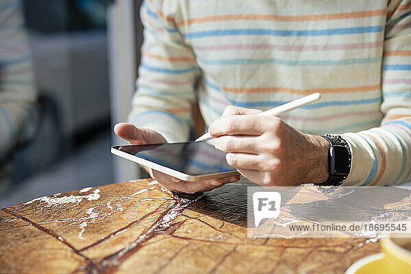 Mann benutzt Tablet-Computer mit digitalisiertem Stift im Café
