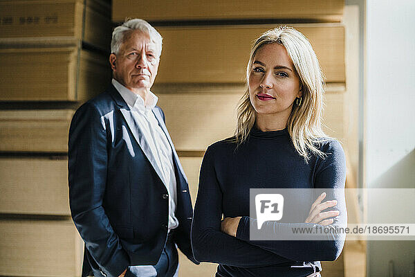 Businesswoman with arms crossed standing by colleague in factory