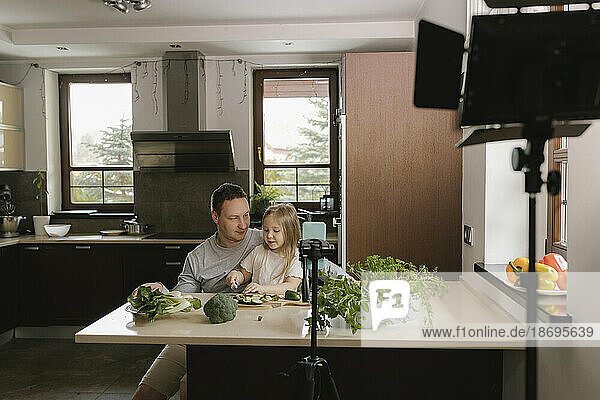 Father and daughter cutting vegetable filming tutorial at home