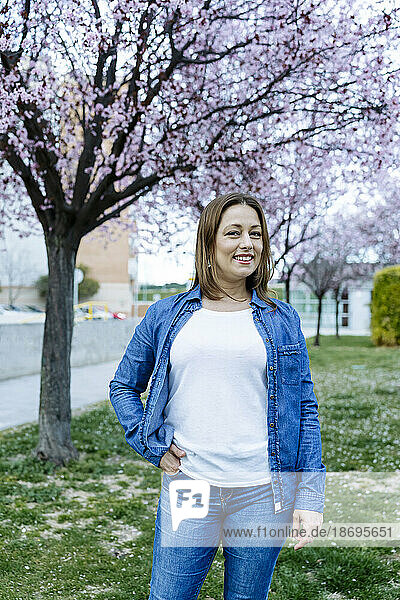 Smiling woman with hand in pocket standing at park