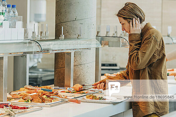 Woman taking food in plate standing by buffet