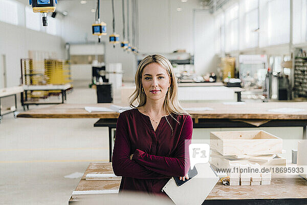 Confident businesswoman with arms crossed in carpentry factory