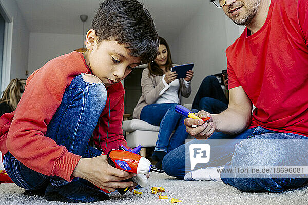 Father and son playing with toys sitting in living room at home